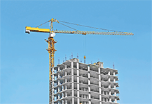 Photo of a crane high above a building under construction against the backdrop of a blue sky
