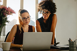 Two businesswoman loking at a laptop screen