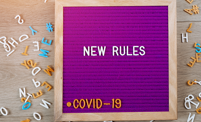 A purple letter board, reading New Rules in white letters, COVID-19 in yellow letters, and various color letters scattered on each side.