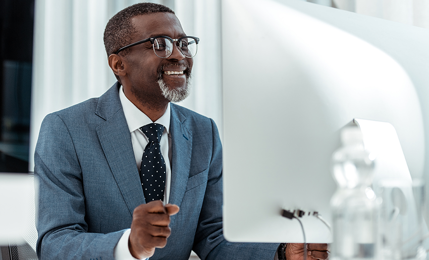 Smiling African American businessman please with working at his desktop computer.