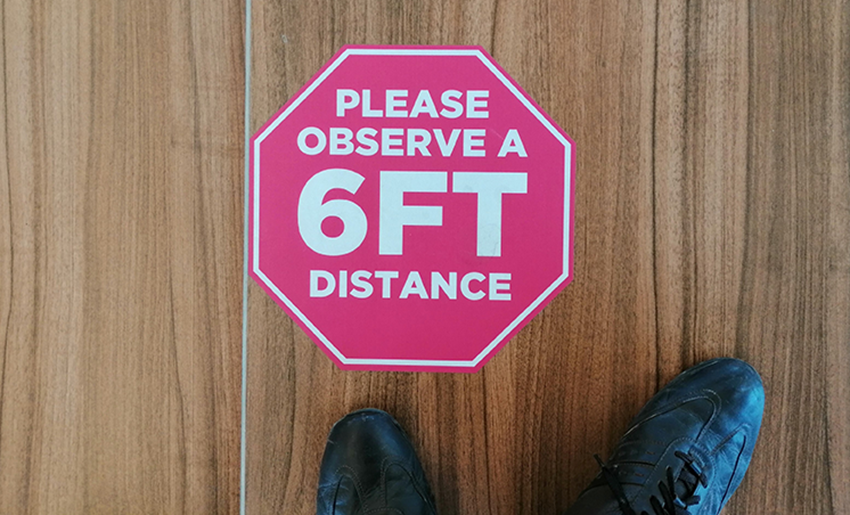 A red octagon sticker reading,' Please observe a 6 feet distance,