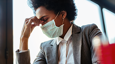 Exhausted African American businesswoman wearing facemask.