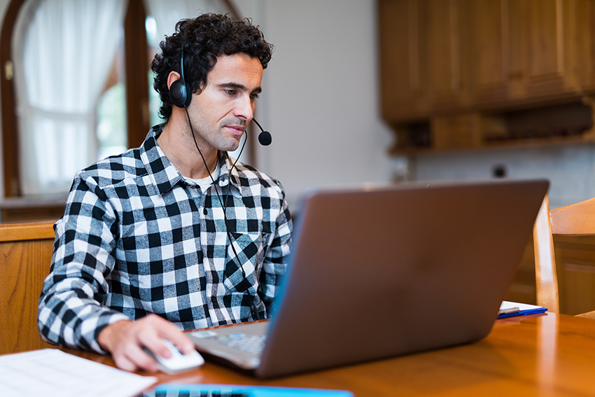 Man with phone headset worknig at his computer from home