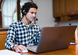 Man with phone headset worknig at his computer from home