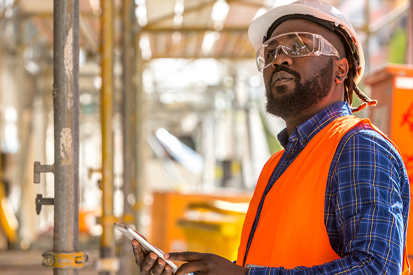 African American construction supervisor surveying his jobsite with a tablet computer in hand