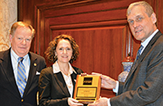 Chris Carey, Davina Weinstein and NYSIF Rep Stephen Lieber holding plaque recognizing Harmonie Club for 75 years as a NYSIF customer