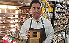 Kei Wada holding plaque recognizing Katagiri Inc for 75 years as a NYSIF customer