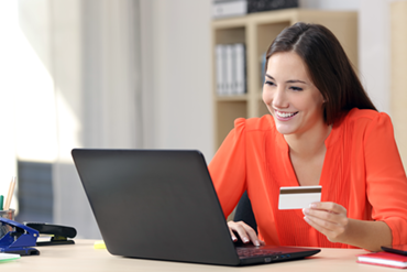 Smiling woman holding credit card at laptop computer