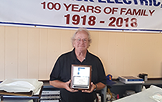 Brian Radzwill holding plaque recognizing Quermback Electric Inc for 75 years as a NYSIF customer