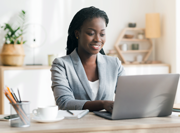 Young woman sitting in modern office typing at her laptop