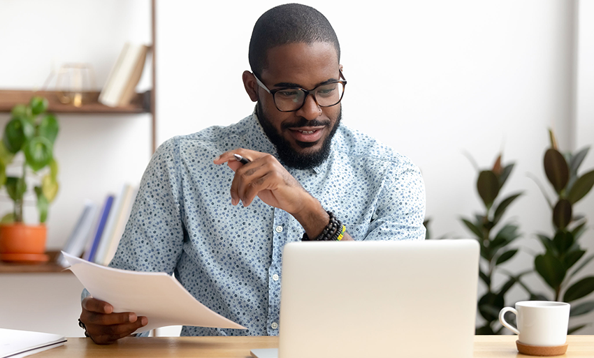 African American businessman sitting behind a laptop looking pleased at his computer screen