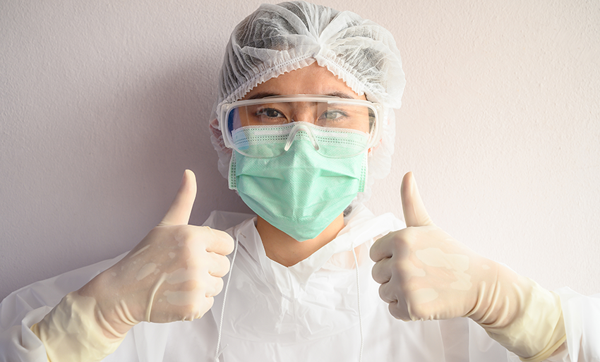 Photo of an Asian woman in hairnet, facemask and latex gloves giving the thumbs up sign with both hands